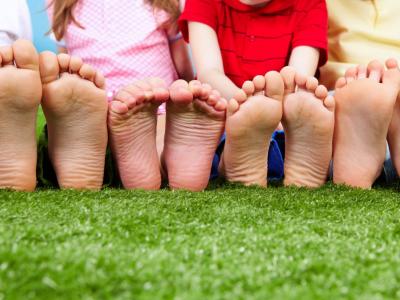 Imagem mostra pés de crianças sentadas na grama