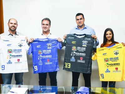 A imagem mostra os representantes do acordo segurando camisas do time