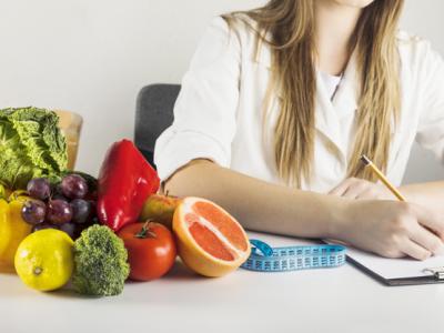 A imagem mostra uma nutricionista com alimentos em uma mesa